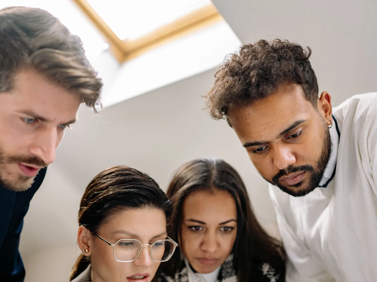 Four colleagues gathered around a laptop reviewing a store plan together